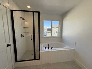 Full bath featuring a textured ceiling, a stall shower, a garden tub, and tile patterned floors