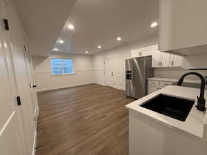 Kitchen featuring dark wood-style flooring, recessed lighting, white cabinetry, high quality fridge, and a sink