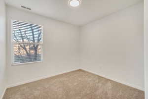 Empty room featuring carpet floors, visible vents, and baseboards