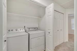 Clothes washing area featuring laundry area, light carpet, and independent washer and dryer