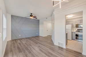 Unfurnished living room featuring visible vents, ceiling fan, light wood-style flooring, and baseboards