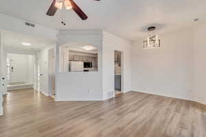 Unfurnished living room with ceiling fan, light wood finished floors, and visible vents