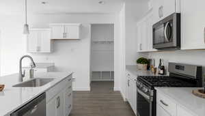 Kitchen featuring light countertops, appliances with stainless steel finishes, a sink, and white cabinetry