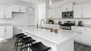 Kitchen with stainless steel appliances, a breakfast bar, a sink, and dark wood finished floors