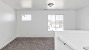 Carpeted empty room featuring baseboards and visible vents