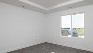 Spare room featuring baseboards, visible vents, and dark colored carpet