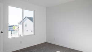 Unfurnished room featuring dark colored carpet and baseboards