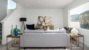 Carpeted living area featuring stairway and baseboards