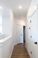 Hall with dark wood-type flooring, visible vents, and baseboards