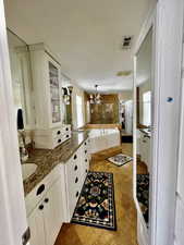 Full bath featuring a tub, visible vents, vanity, and an inviting chandelier