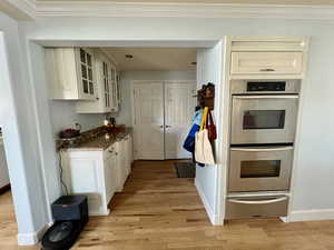 Kitchen featuring double oven, glass insert cabinets, a warming drawer, and light wood finished floors