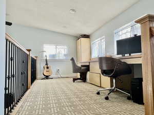 Office space with a wealth of natural light, a textured ceiling, and baseboards