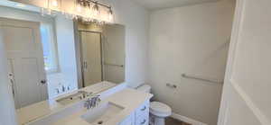 Full bathroom with vanity, baseboards, a shower stall, and toilet