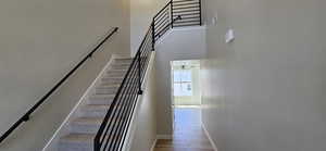 Staircase with baseboards, ceiling fan, wood finished floors, and a towering ceiling