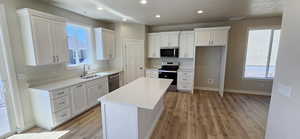 Kitchen with a sink, a center island, stainless steel appliances, and light wood finished floors