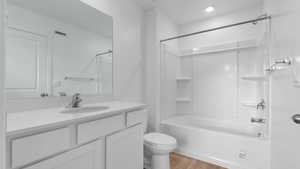 Full bath featuring visible vents, bathing tub / shower combination, toilet, wood finished floors, and vanity