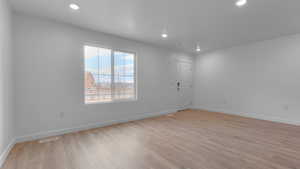 Empty room with light wood-type flooring, visible vents, baseboards, and recessed lighting