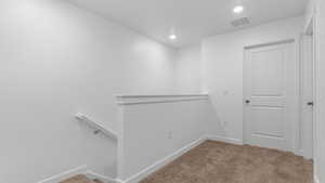 Hall with carpet floors, recessed lighting, visible vents, an upstairs landing, and baseboards