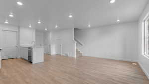 Kitchen with light countertops, light wood finished floors, stainless steel dishwasher, and recessed lighting