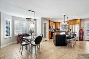 Kitchen featuring stainless steel appliances, dark countertops, tasteful backsplash, light tile patterned flooring, and a kitchen island