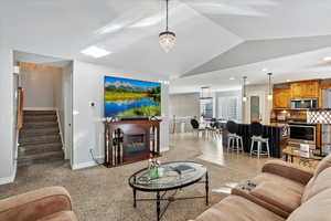 Living room featuring light carpet, light tile patterned floors, an inviting chandelier, stairs, and vaulted ceiling