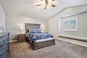 Carpeted bedroom with lofted ceiling, ceiling fan, visible vents, and baseboards