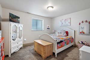 Carpeted bedroom featuring visible vents, a textured ceiling, and baseboards