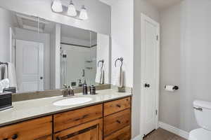 Bathroom featuring baseboards, toilet, tile patterned flooring, vanity, and a shower stall