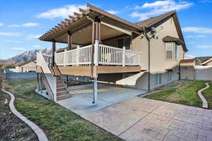 Back of house featuring stairway, a deck with mountain view, fence, a yard, and stucco siding