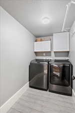 Laundry room featuring baseboards, independent washer and dryer, cabinet space, and wood tiled floor