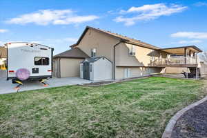 Back of property featuring an outbuilding, stucco siding, a yard, and a shed