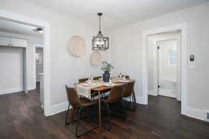 Dining room featuring dark wood-style floors, an inviting chandelier, and baseboards