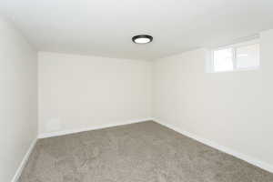 Carpeted spare room featuring a textured ceiling and baseboards