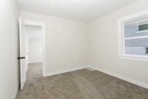 Empty room featuring carpet, visible vents, and baseboards