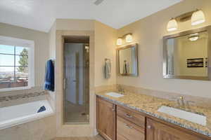 Full bathroom featuring double vanity, a garden tub, a shower stall, and a sink