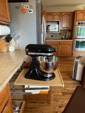 Kitchen with stainless steel appliances, light countertops, brown cabinetry, and wood finished floors