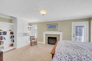 Carpeted bedroom with baseboards, crown molding, and a fireplace