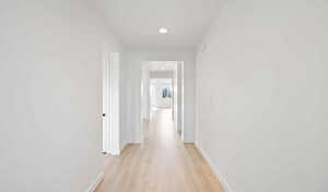 Hallway with light wood-style flooring, baseboards, and recessed lighting