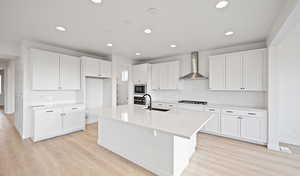 Kitchen with gas stovetop, a sink, stainless steel oven, built in microwave, and wall chimney exhaust hood