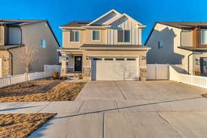 View of front of property with solar panels, board and batten siding, stone siding, and fence