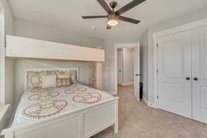 Bedroom featuring a closet, baseboards, a ceiling fan, and light colored carpet