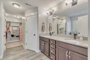 Bathroom featuring visible vents, a sink, a shower stall, and wood finished floors