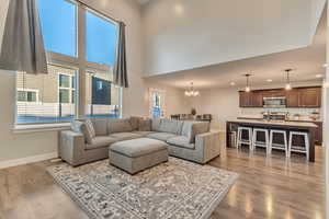 Living room with light wood-type flooring, plenty of natural light, a towering ceiling, and baseboards