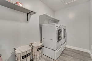 Clothes washing area featuring laundry area, washer and clothes dryer, light wood-style flooring, and baseboards