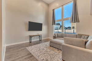 Living room featuring a towering ceiling, baseboards, and wood finished floors