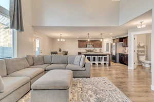 Living area with light wood-style floors, recessed lighting, a high ceiling, and an inviting chandelier