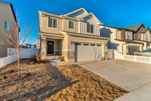 View of front of property featuring a garage, stone siding, board and batten siding, and fence