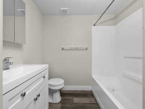 Bathroom with shower / bathtub combination, toilet, wood type finished floors, and baseboards