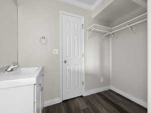 Bathroom featuring crown molding, vanity, baseboards, and wood finished floors