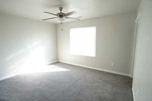 Empty room featuring carpet floors, a ceiling fan, visible vents, and baseboards